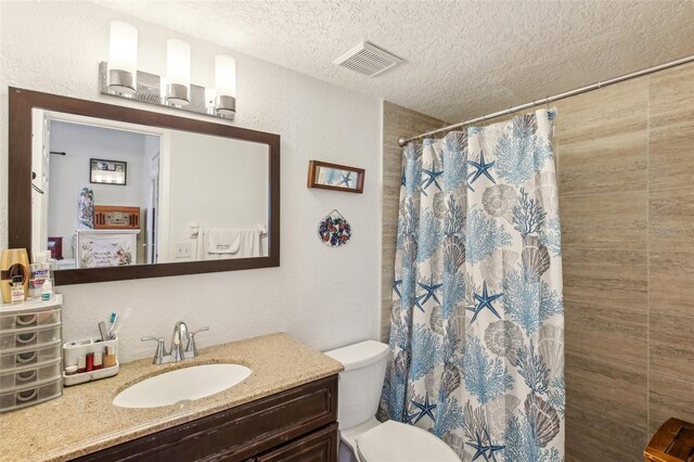 bathroom featuring vanity, toilet, a textured ceiling, and walk in shower