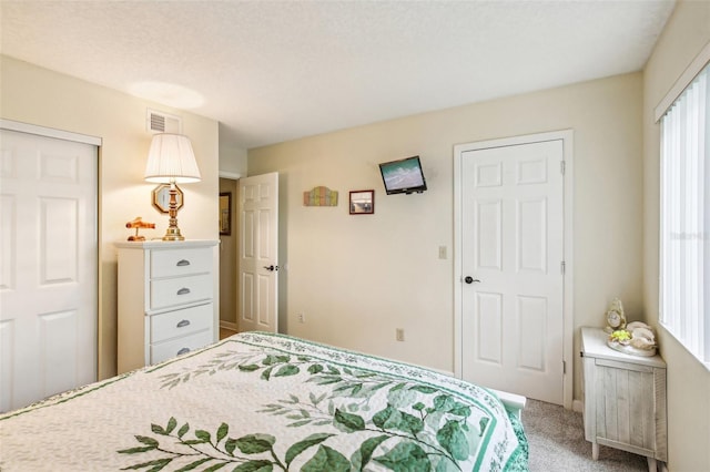 carpeted bedroom with visible vents and a textured ceiling