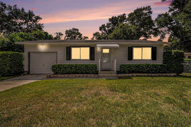 ranch-style house featuring a garage and a lawn