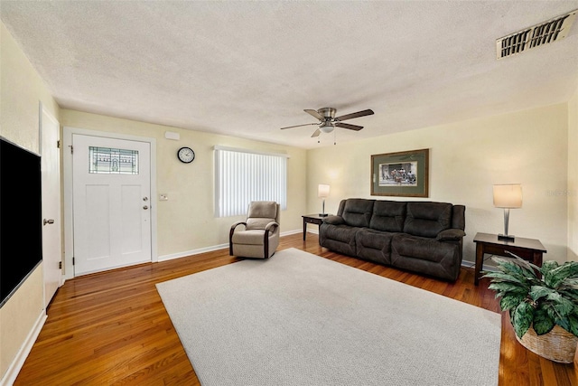 living room with ceiling fan, hardwood / wood-style flooring, and a textured ceiling