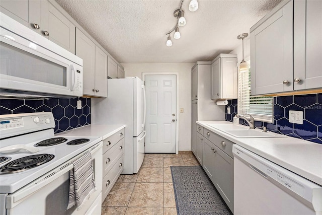 kitchen featuring rail lighting, tasteful backsplash, sink, pendant lighting, and white appliances