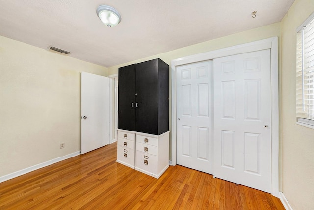 unfurnished bedroom with light hardwood / wood-style flooring and a closet