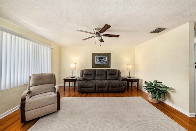 living room with ceiling fan, dark hardwood / wood-style floors, and a textured ceiling