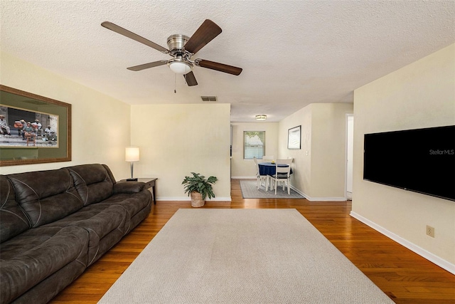 living room featuring ceiling fan, hardwood / wood-style flooring, and a textured ceiling