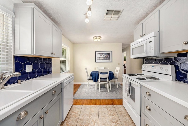 kitchen with white cabinetry, sink, white appliances, and a textured ceiling