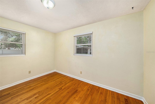 spare room featuring hardwood / wood-style flooring and a textured ceiling