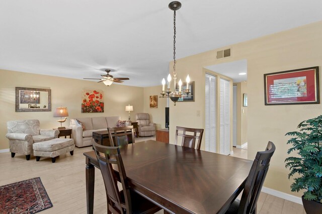 dining area featuring light hardwood / wood-style flooring and ceiling fan with notable chandelier