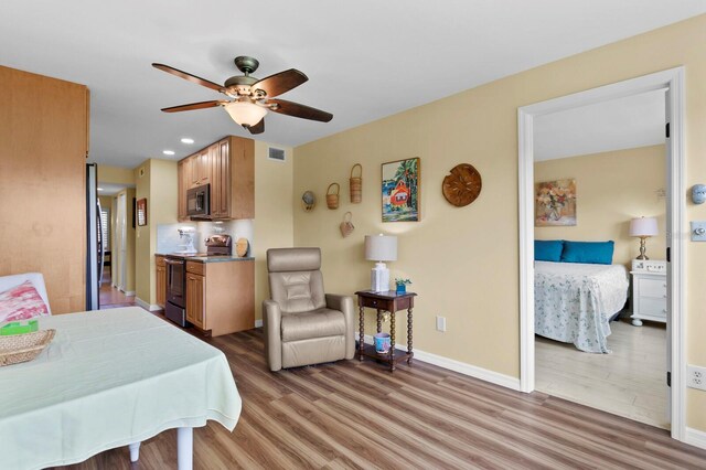 bedroom with hardwood / wood-style floors, stainless steel refrigerator, and ceiling fan