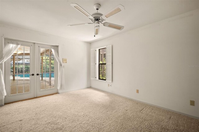 carpeted spare room featuring ceiling fan and french doors