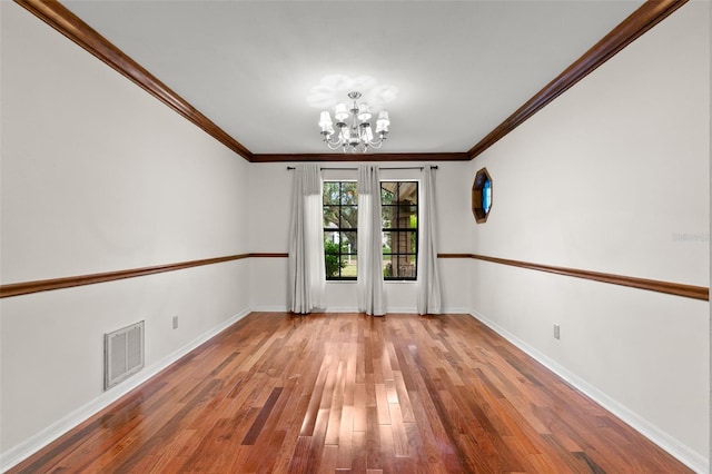 empty room with a notable chandelier, wood-type flooring, and crown molding