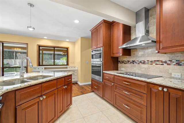 kitchen featuring light stone countertops, wall chimney exhaust hood, black electric cooktop, sink, and light tile patterned floors