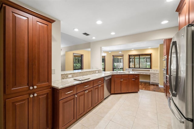 kitchen featuring sink, appliances with stainless steel finishes, light tile patterned flooring, light stone counters, and kitchen peninsula