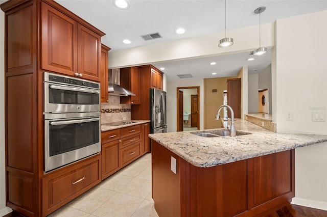 kitchen featuring pendant lighting, sink, wall chimney exhaust hood, appliances with stainless steel finishes, and kitchen peninsula