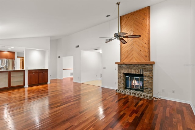 unfurnished living room with ceiling fan, hardwood / wood-style flooring, high vaulted ceiling, and a brick fireplace