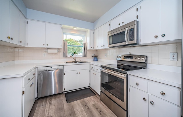 kitchen featuring light wood-type flooring, white cabinetry, tasteful backsplash, and stainless steel appliances