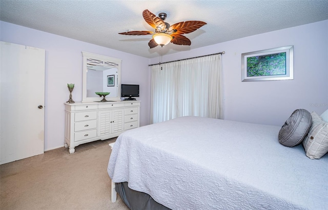 bedroom featuring ceiling fan, light colored carpet, and a textured ceiling