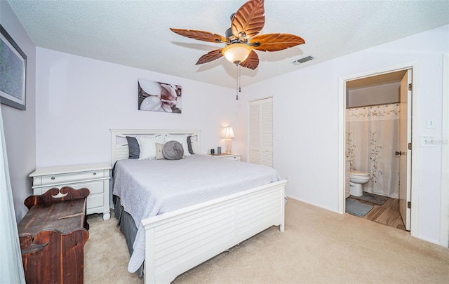 carpeted bedroom featuring ceiling fan, a closet, a textured ceiling, and ensuite bathroom