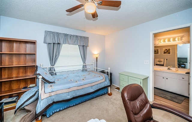 carpeted bedroom featuring sink, ceiling fan, a textured ceiling, and ensuite bath