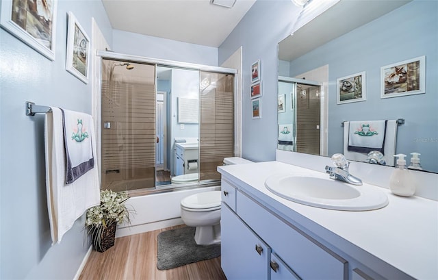 full bathroom featuring shower / bath combination with glass door, toilet, hardwood / wood-style floors, and vanity