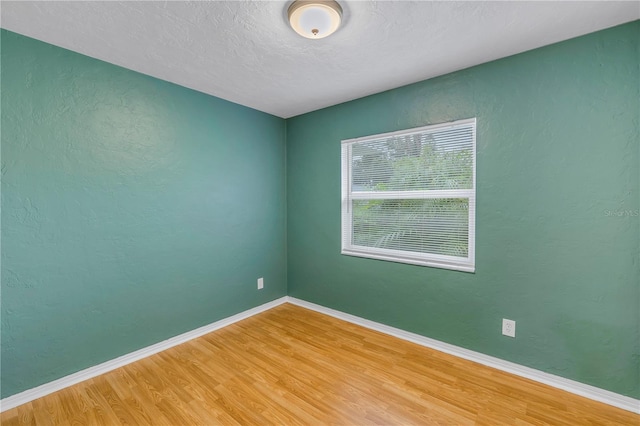 unfurnished room with a textured ceiling and wood-type flooring