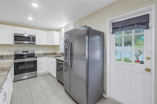 kitchen with light stone countertops, stainless steel appliances, sink, white cabinets, and light tile patterned flooring