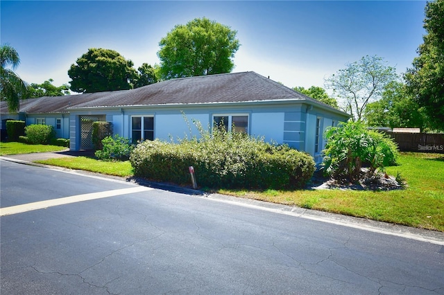 view of front of property featuring a yard, fence, and stucco siding