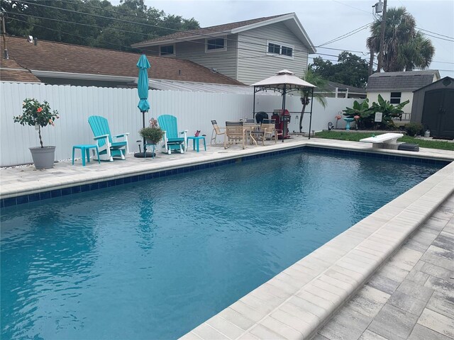 view of pool featuring a diving board, a storage shed, and a patio