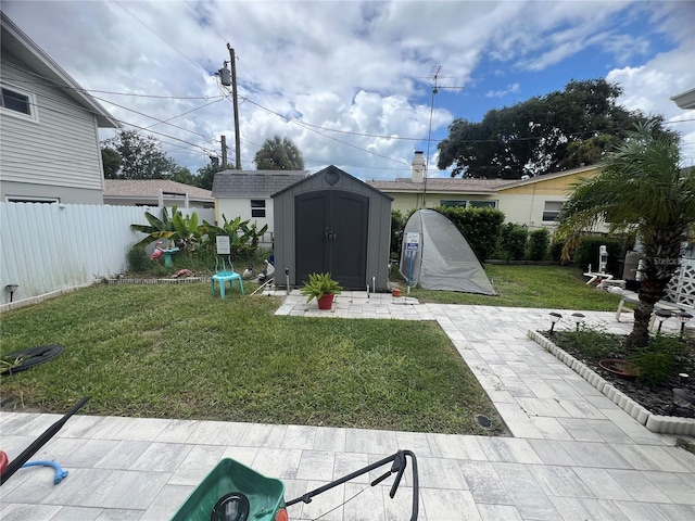 view of yard with a storage shed, a fenced backyard, a patio, and an outbuilding