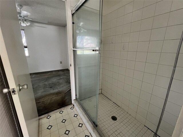 full bathroom featuring tile patterned flooring, plenty of natural light, a textured ceiling, and a shower stall