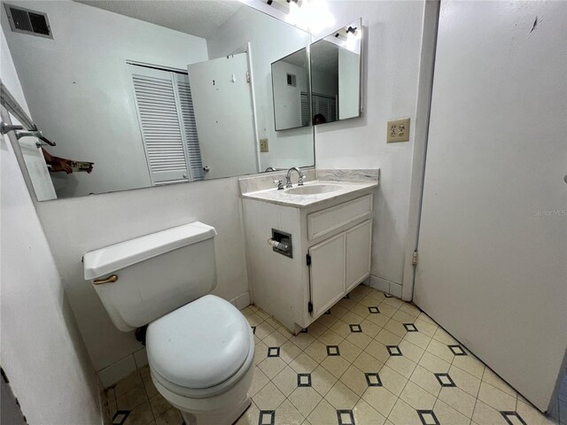 bathroom featuring tile patterned flooring, visible vents, vanity, and toilet