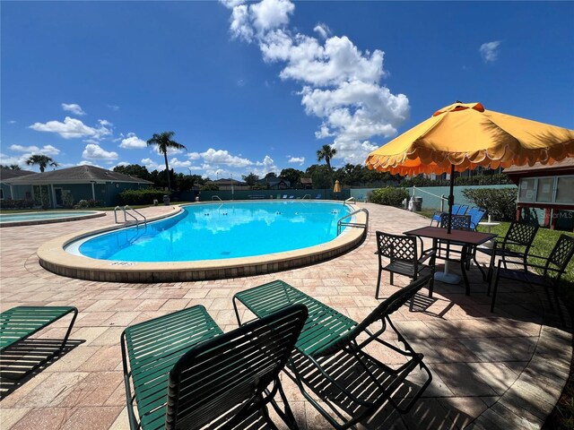 pool with a patio area and fence