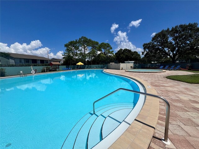 community pool featuring a community hot tub, fence, and a patio