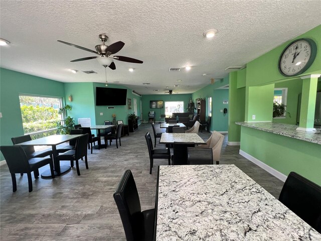 dining space with ceiling fan, a textured ceiling, visible vents, and baseboards