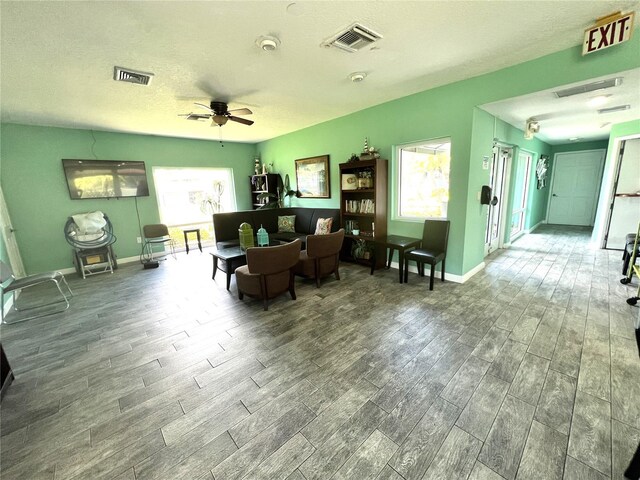 interior space featuring baseboards, visible vents, ceiling fan, a textured ceiling, and wood finish floors