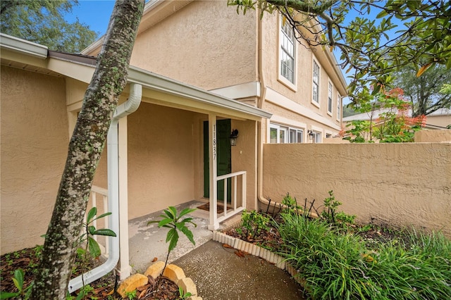 property entrance featuring fence and stucco siding