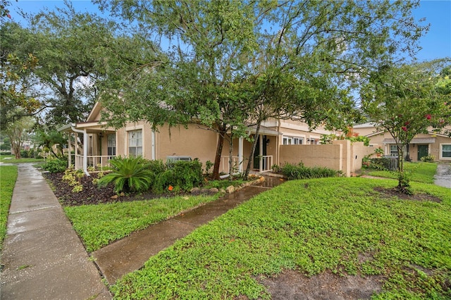 view of front of house featuring fence, a front lawn, and stucco siding