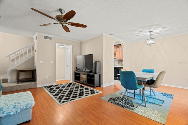 living room with ceiling fan, a textured ceiling, light hardwood / wood-style floors, and ornamental molding