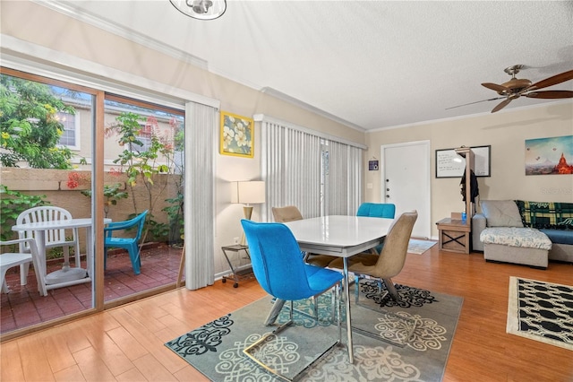 dining space with a textured ceiling, wood finished floors, a ceiling fan, and crown molding