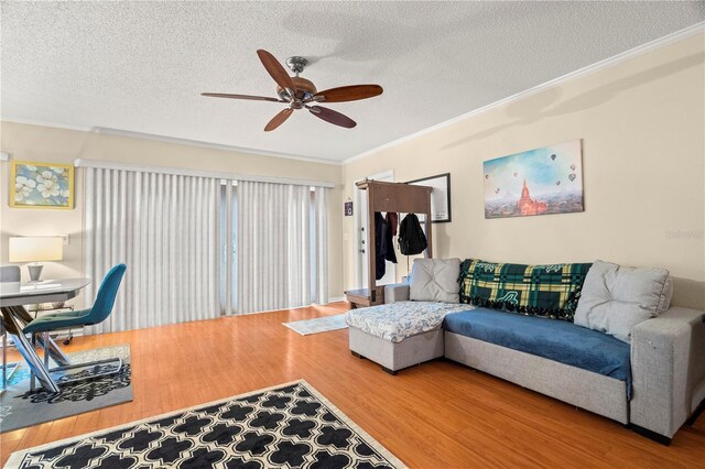 living area featuring ornamental molding, ceiling fan, a textured ceiling, and wood finished floors