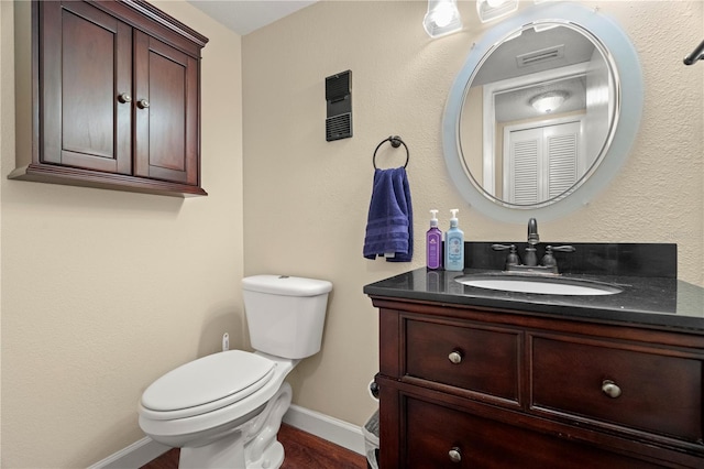 half bathroom featuring visible vents, vanity, toilet, and baseboards