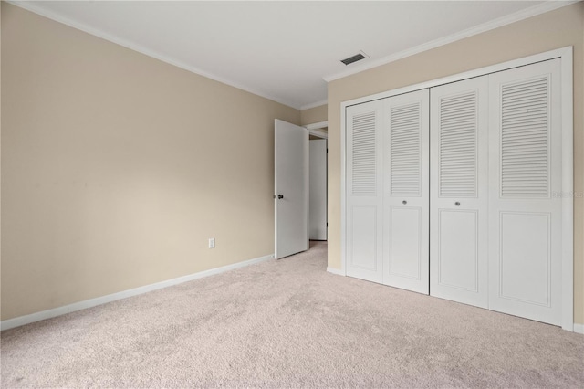 unfurnished bedroom with light colored carpet, visible vents, baseboards, a closet, and crown molding