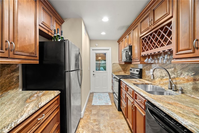 kitchen featuring light stone counters, a sink, brown cabinets, decorative backsplash, and black appliances