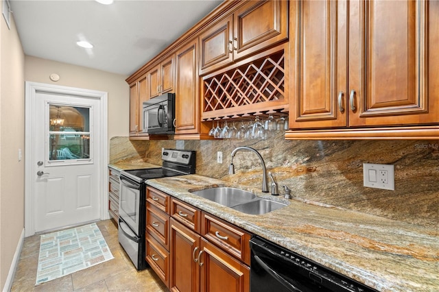 kitchen featuring black appliances, light stone counters, brown cabinets, and a sink