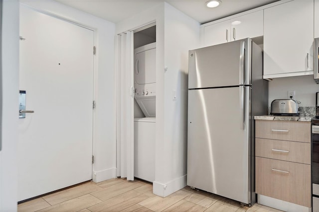 kitchen with stainless steel fridge, light hardwood / wood-style flooring, and stacked washer and dryer