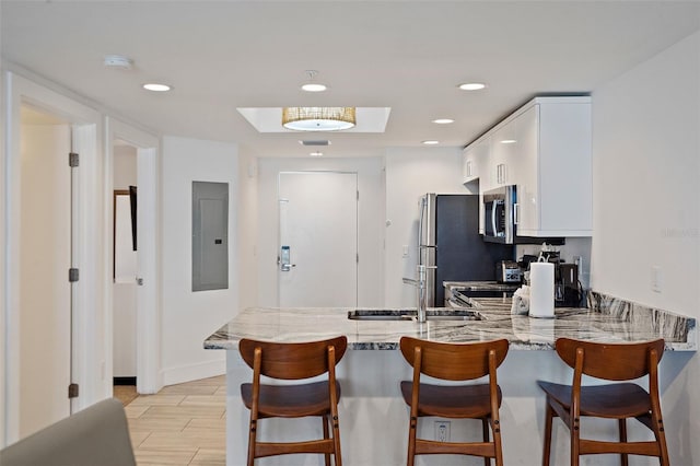 kitchen featuring electric panel, kitchen peninsula, light stone countertops, and white cabinets