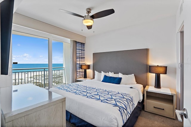 bedroom with carpet, ceiling fan, multiple windows, and a water view