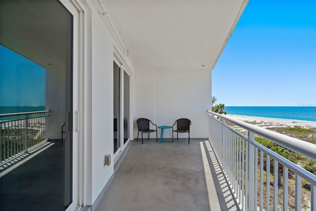 balcony with a water view and a view of the beach