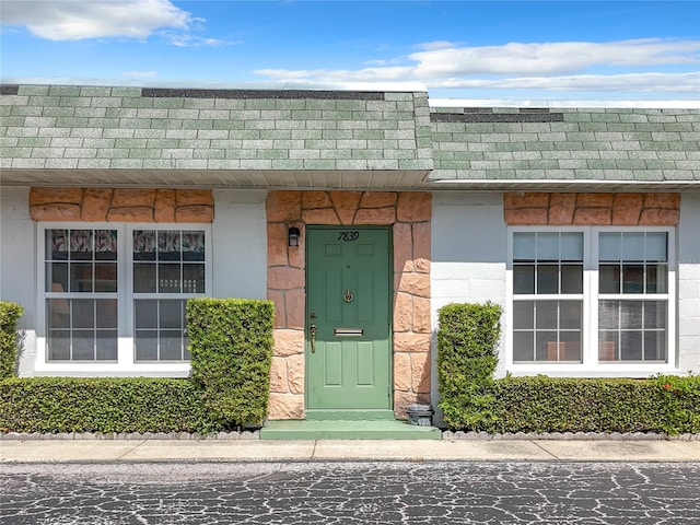 doorway to property with a shingled roof and mansard roof