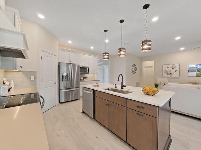 kitchen featuring tasteful backsplash, an island with sink, white cabinets, sink, and stainless steel appliances