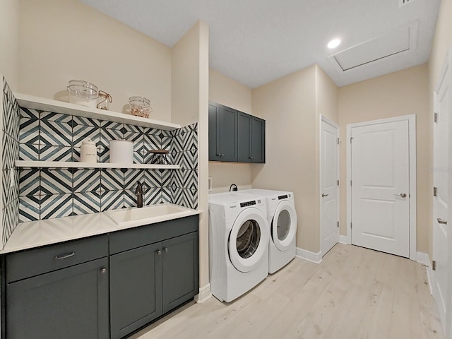 laundry area featuring light wood-type flooring, sink, washing machine and clothes dryer, and cabinets